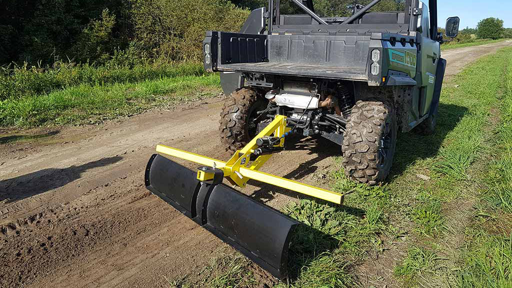 ATV med blad jevner ut grusvei